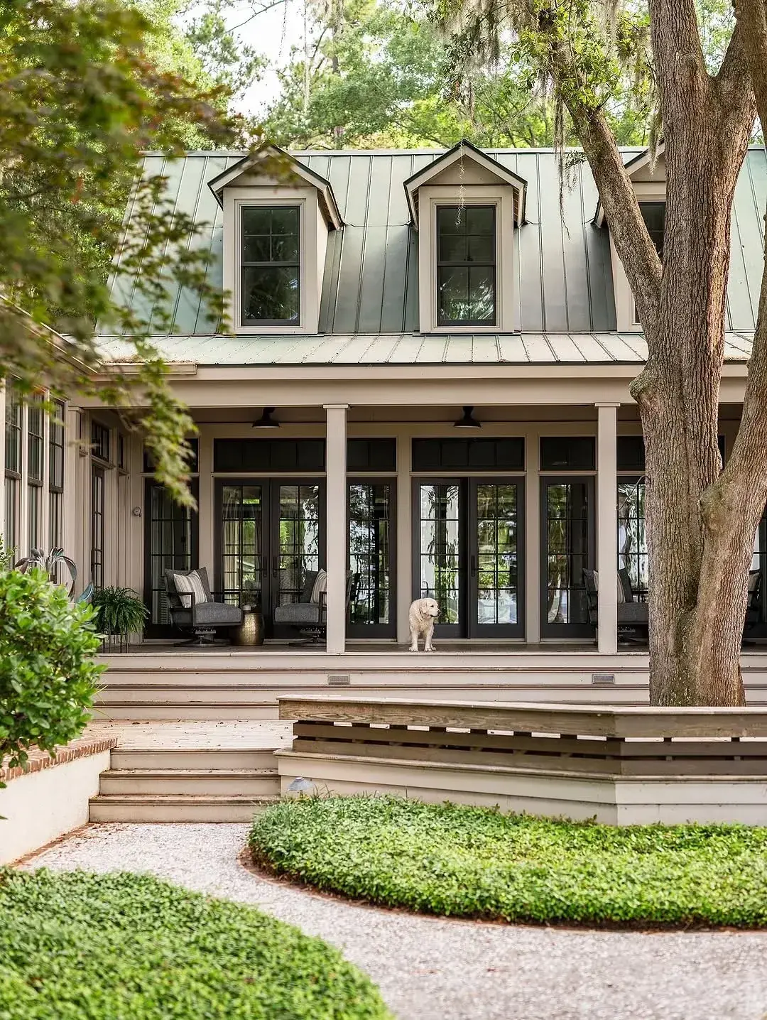 House with a muted green standing seam roof, two dormers and a columned porch with glass doors