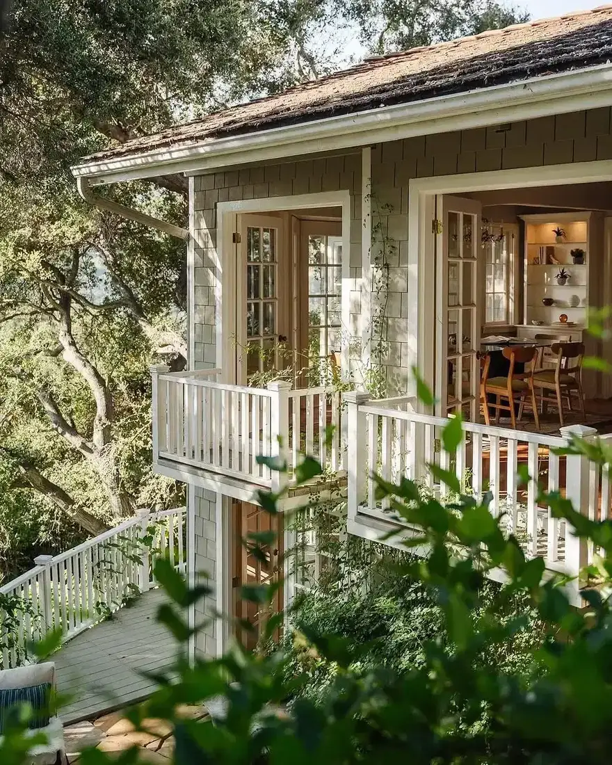 Shingle cottage with a double porch, balcony, and stacked white columns
