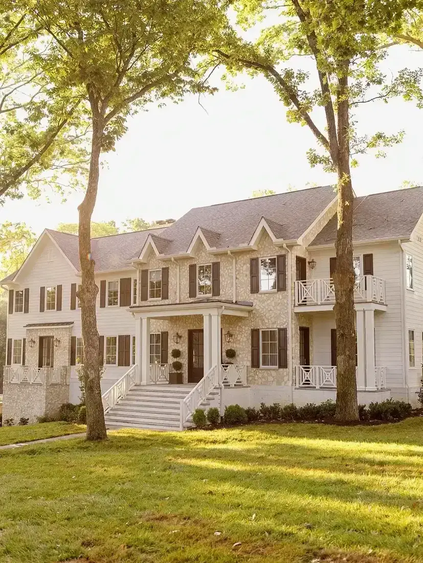 Shingle house with black shutters caught in warm golden evening light