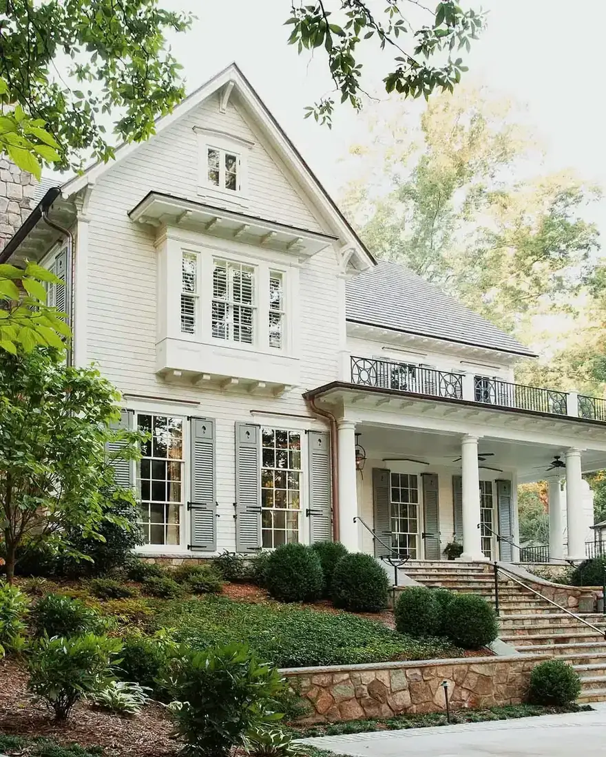 White clapboard house with grey shutters and a wide flight of cut stone steps up to a columned porch