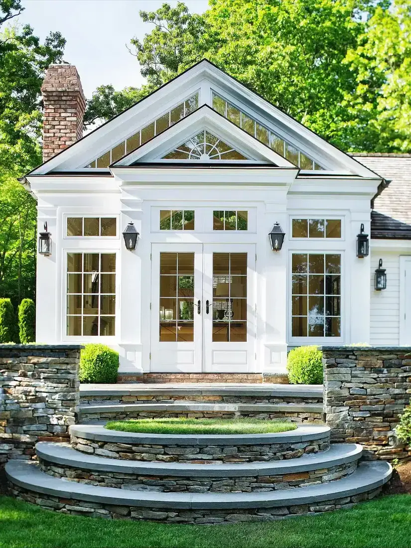 White glazed garden pavilion above curved steps of stacked stone with solid stone treads and a grass landing