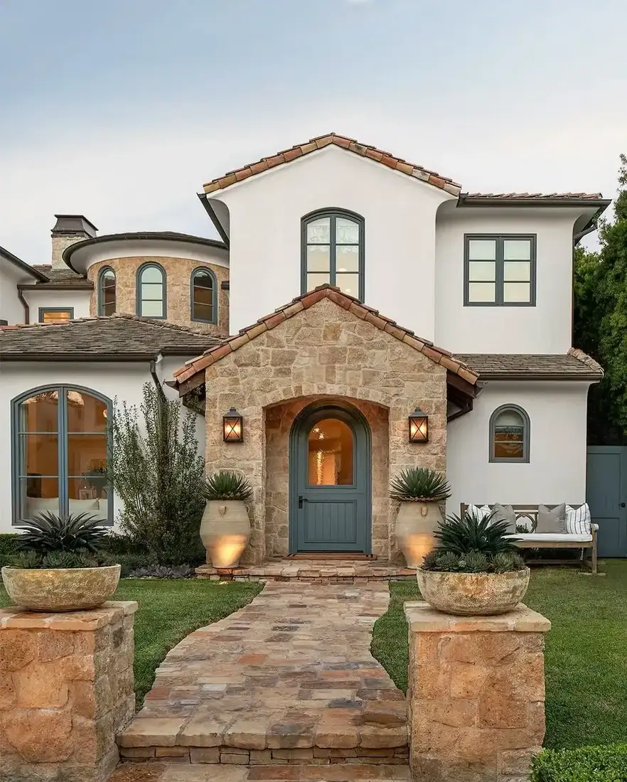 White render house with a stone entry gable, stone garden piers and an irregular flagstone walk