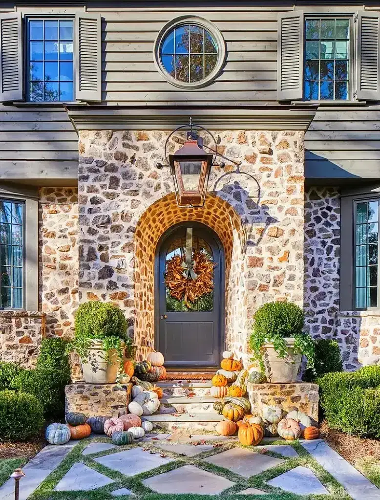 Stone entrance bay with an arched door framed in contrasting voussoirs, grey siding above