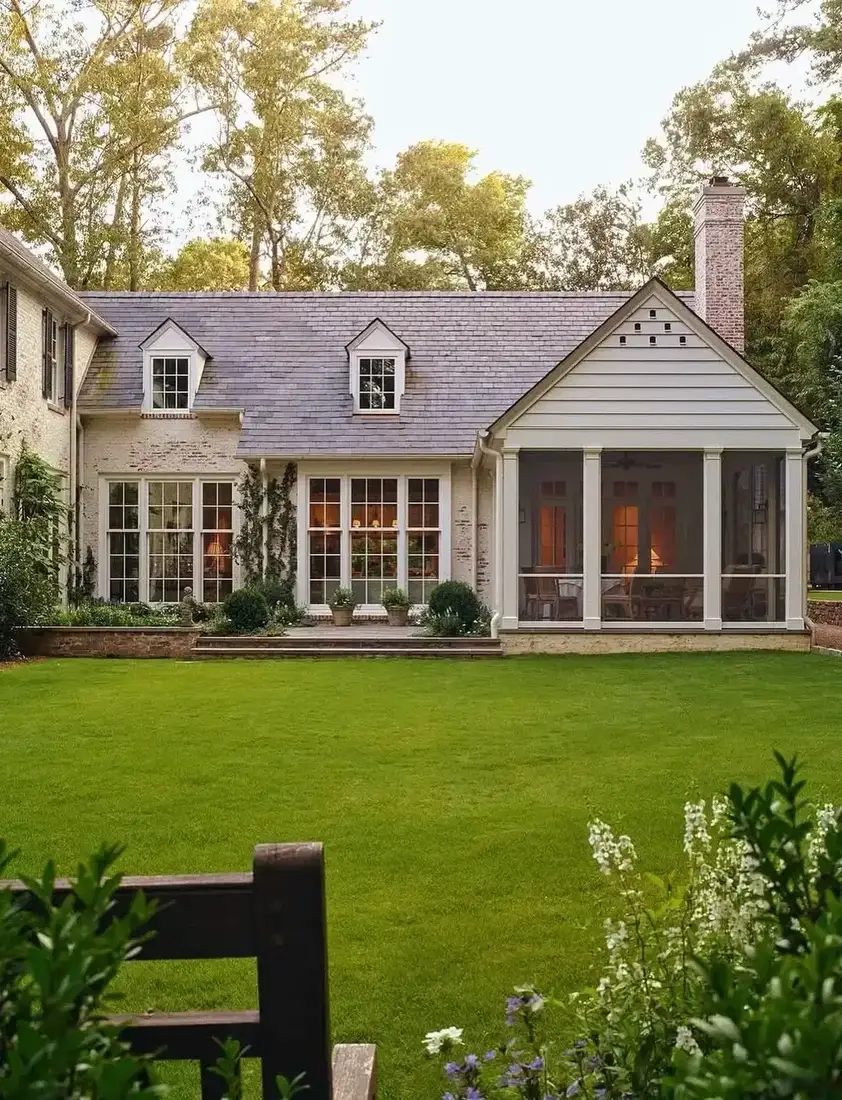Painted brick house with a screened porch and lawn running straight to the walls