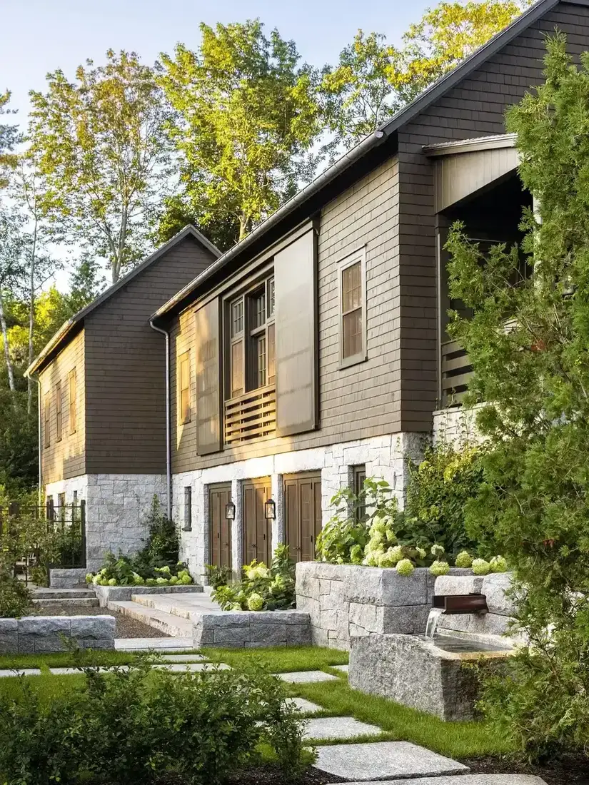 Dark brown clapboard upper storey over a pale granite base with wide steps and a small water spout