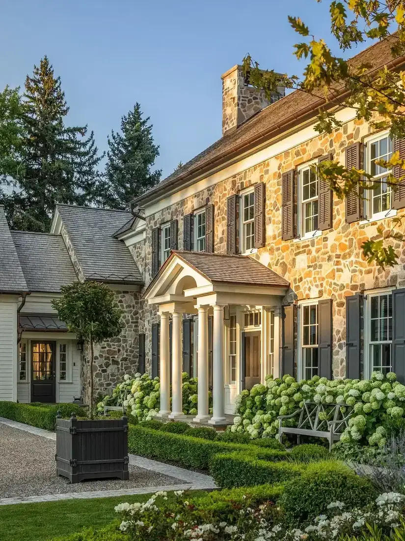 Fieldstone farmhouse with olive shutters and a white columned portico