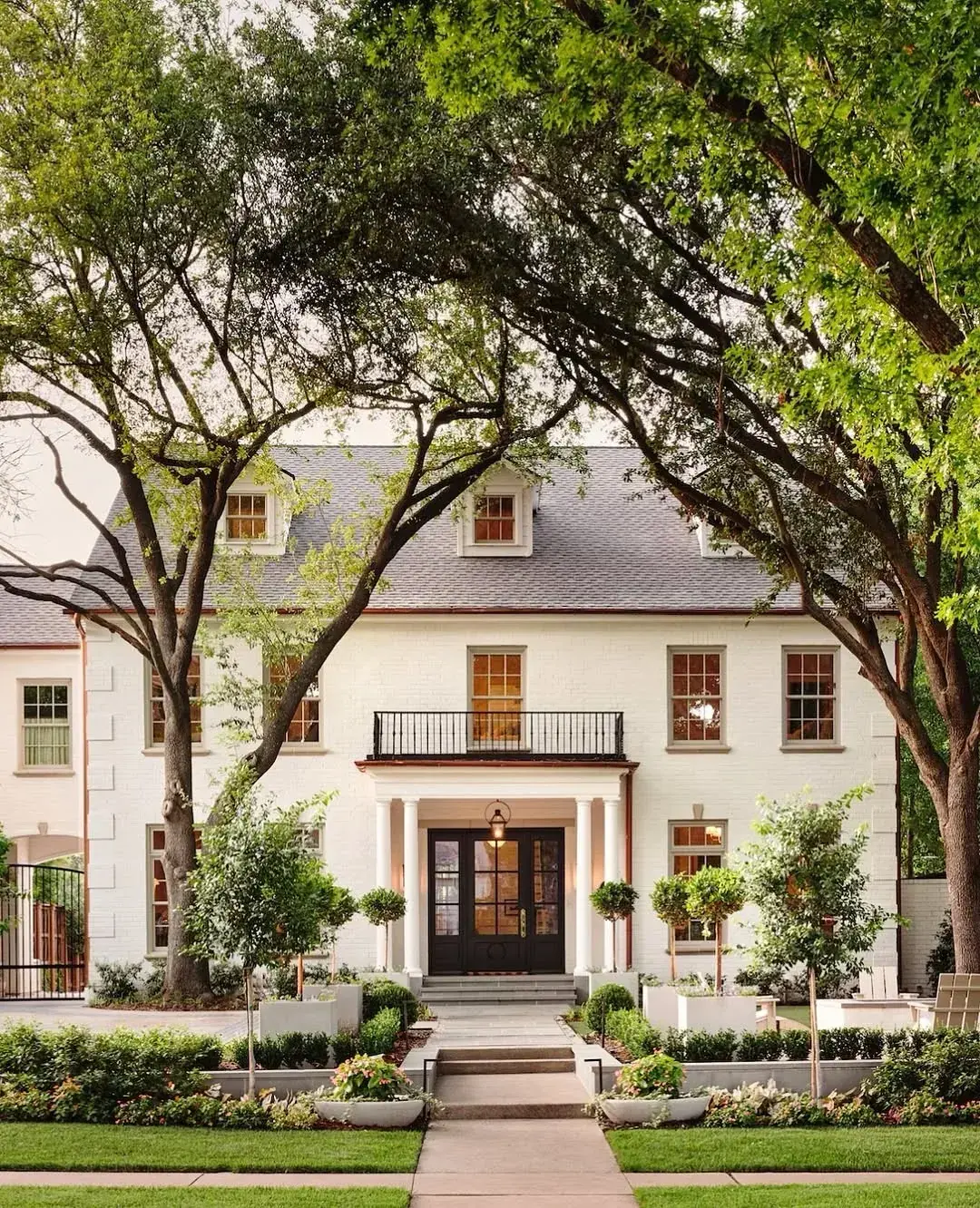Cream rendered house with dark windows, a two column portico and copper downpipes