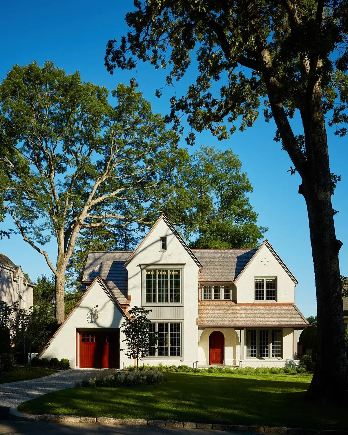 Cream rendered Tudor style house with red garage doors and a red front door