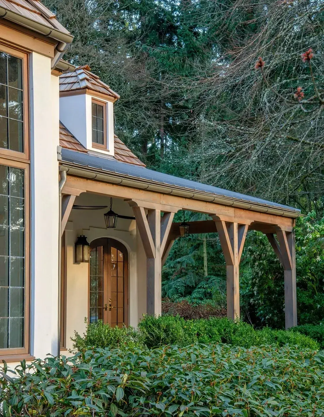 Cream stucco cottage with a timber framed porch and a round headed arched front door