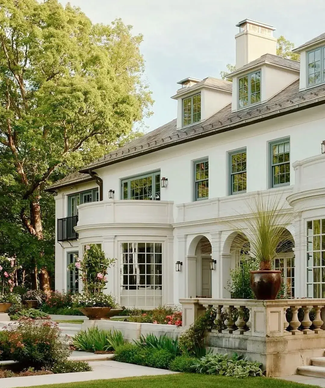 White stucco house with an arched arcade, a curved bay and a stone balustrade terrace