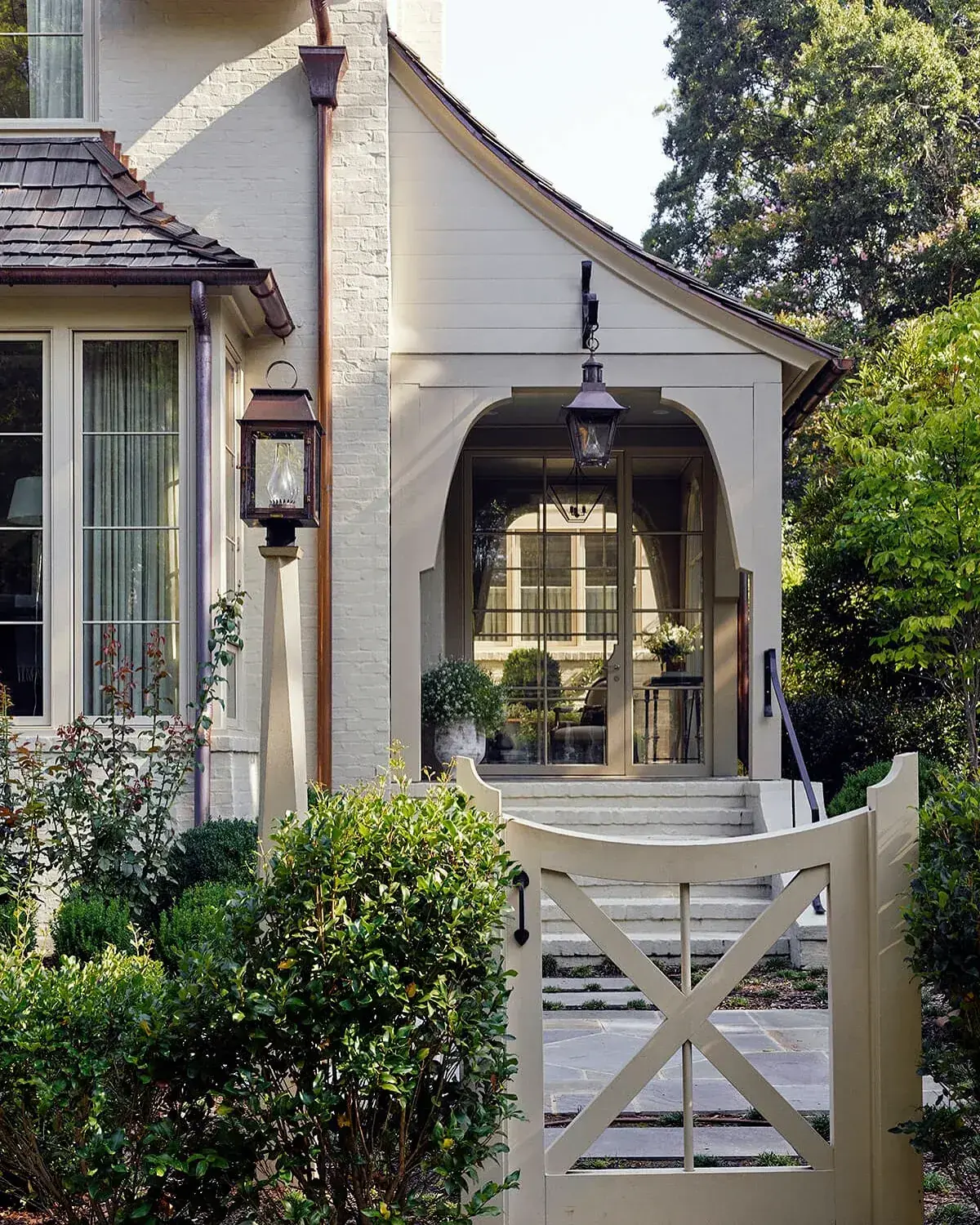 Cream cottage with a shallow arched porch, two lanterns and a cross braced timber gate