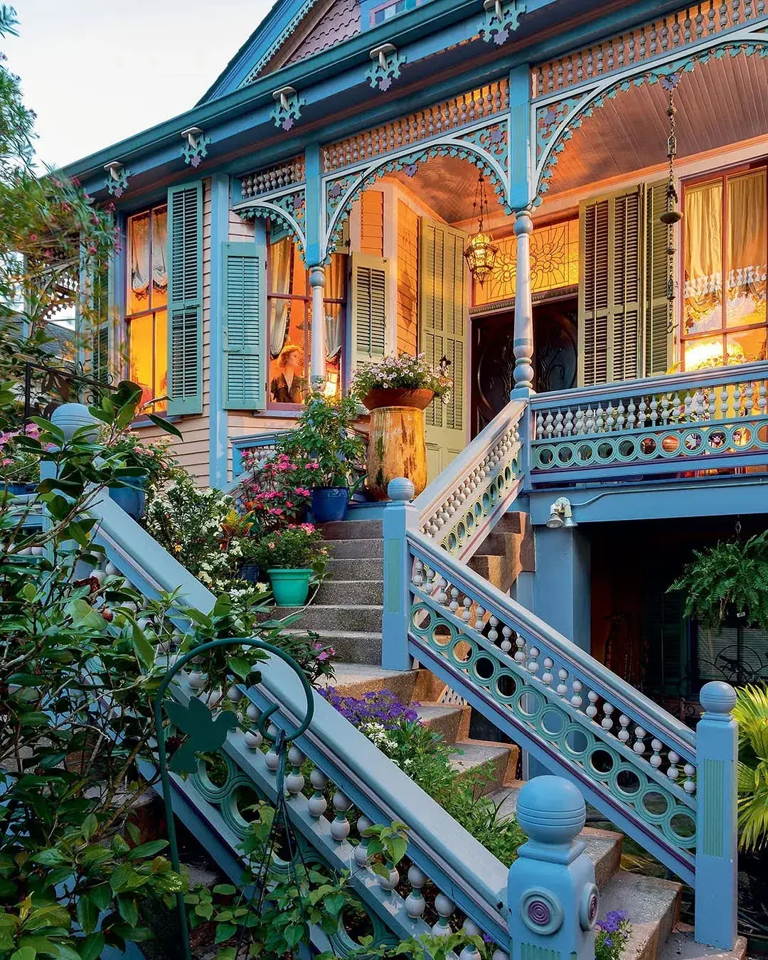 Ornate blue Victorian porch with fretwork arches, shutters and patterned stair rails