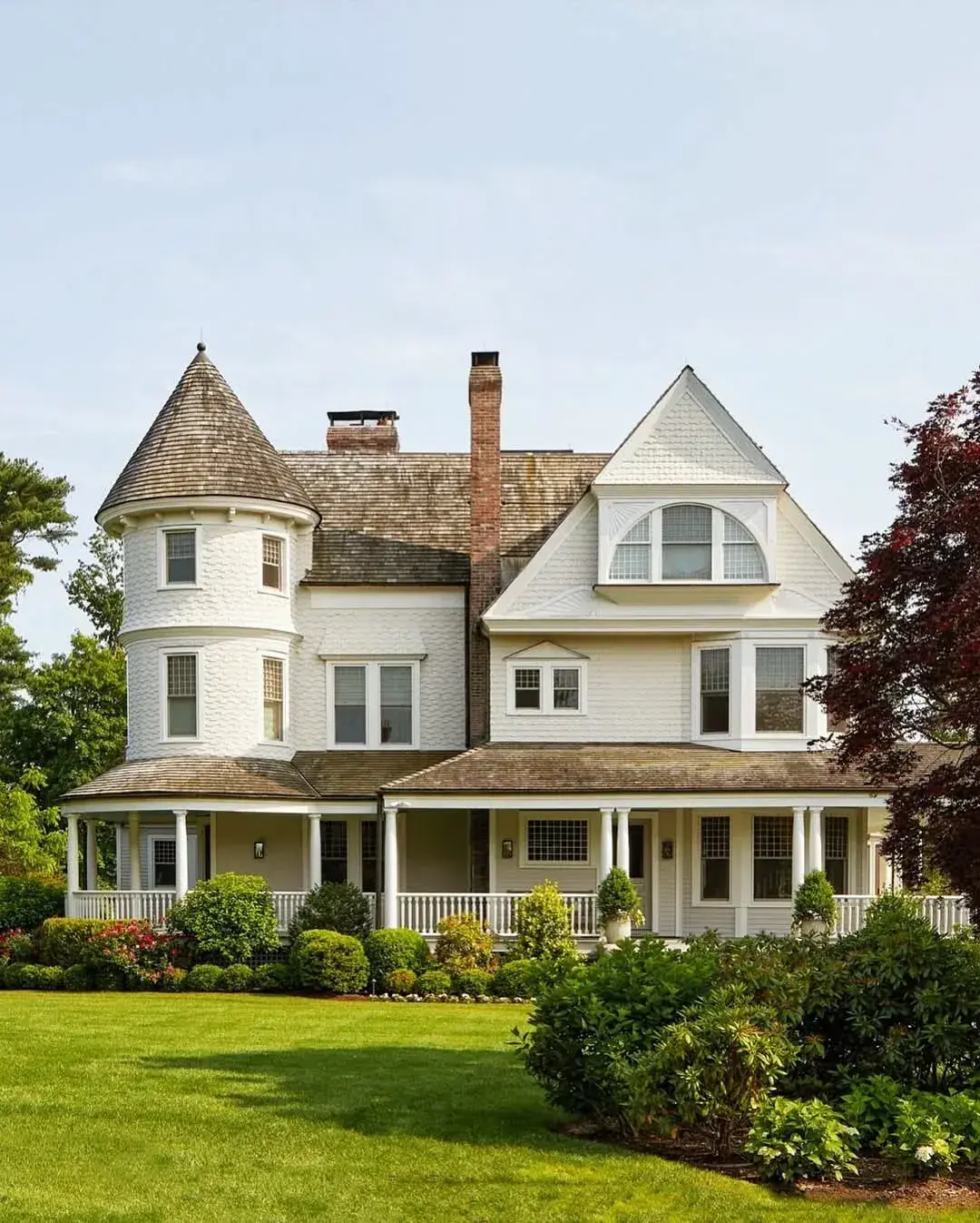 Cream Queen Anne house with round shingle turret and wraparound porch