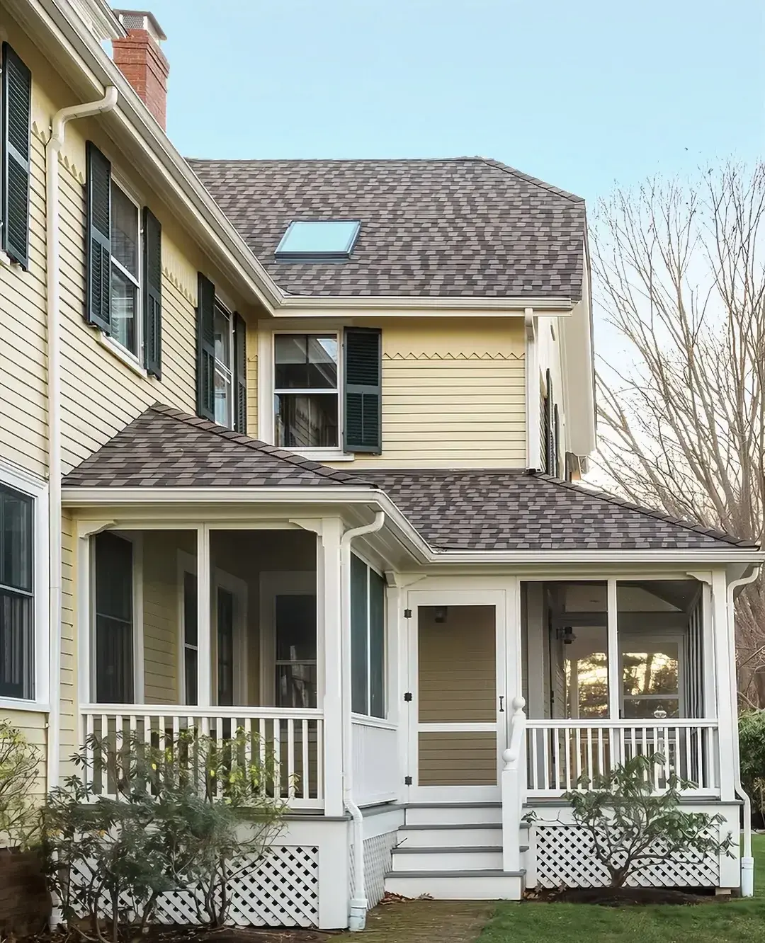 Pale yellow weatherboard house with dark green shutters and enclosed side porch