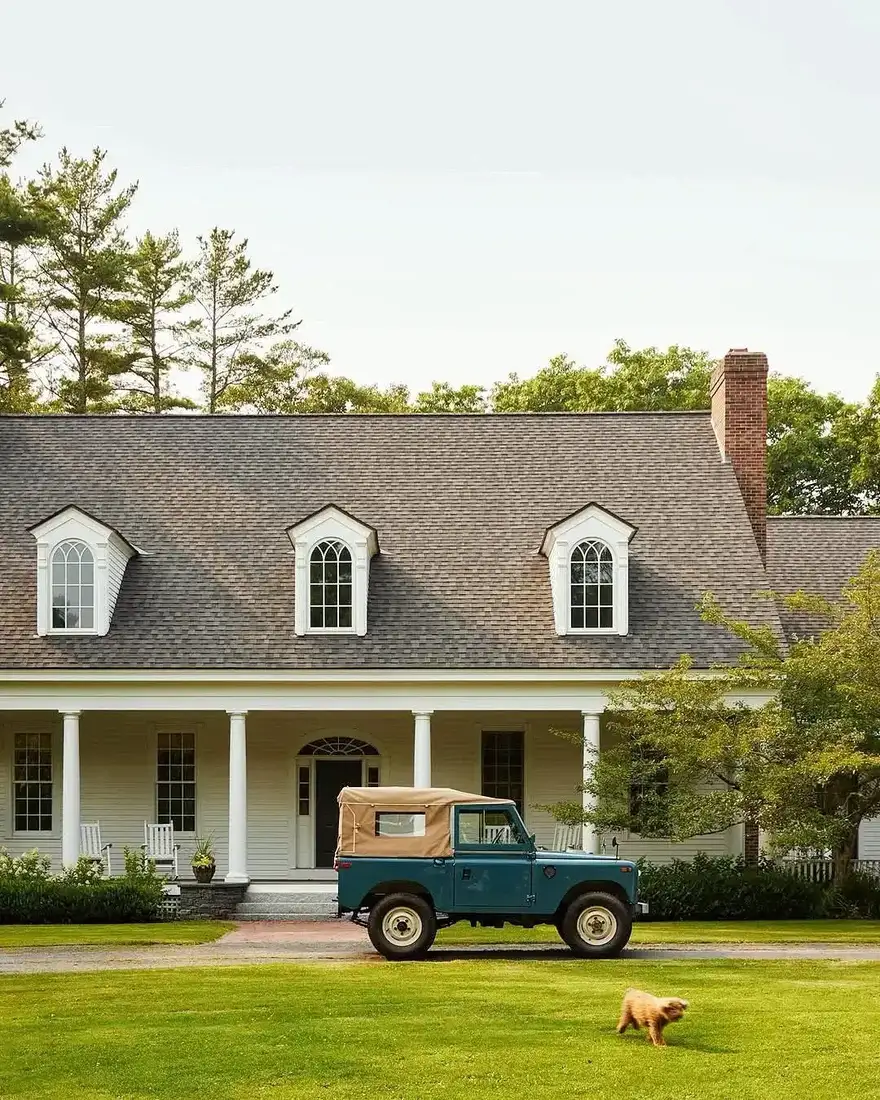 White Cape Cod farmhouse with three dormers and deep porch