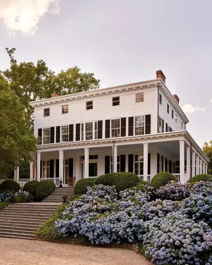 White clapboard house with correctly proportioned black louvred shutters and a deep porch