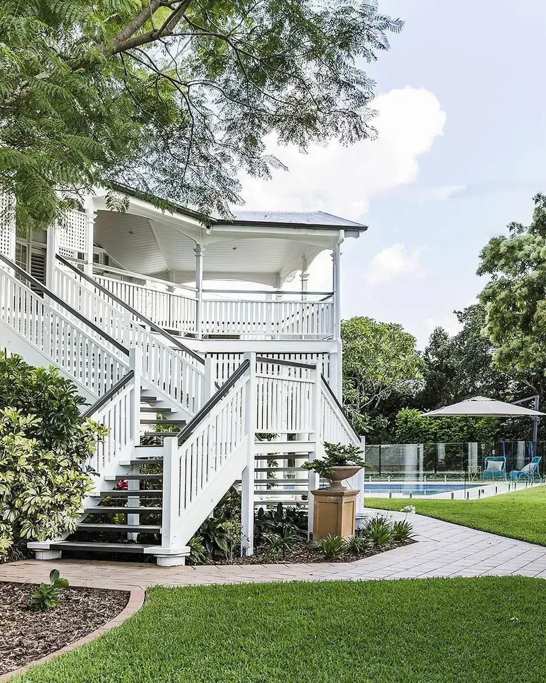 White Queenslander stairs and rails with pool and lawn beyond