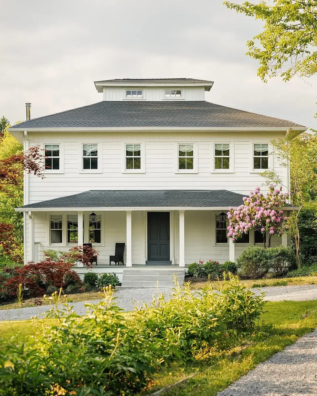 White foursquare house with hip roof, porch and dark front door