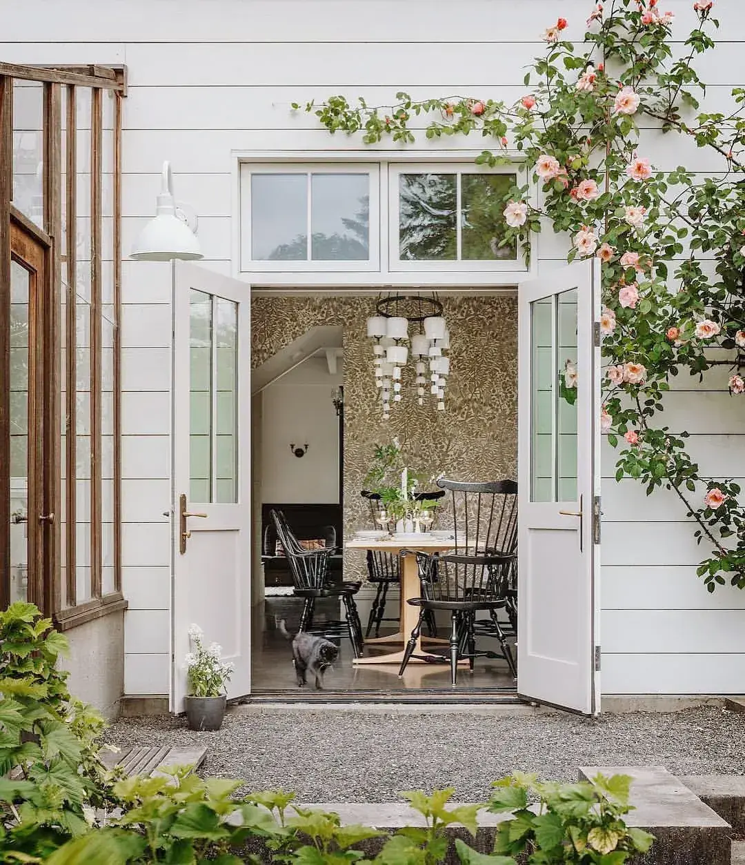 Open French doors with climbing roses over white weatherboard