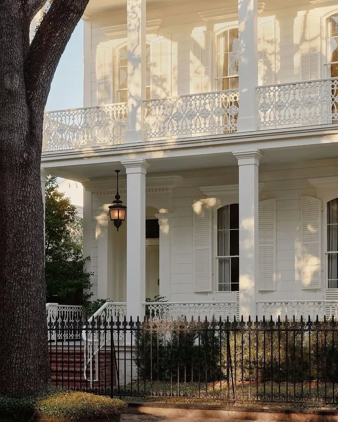 White double gallery townhouse with iron lace rails and black fence