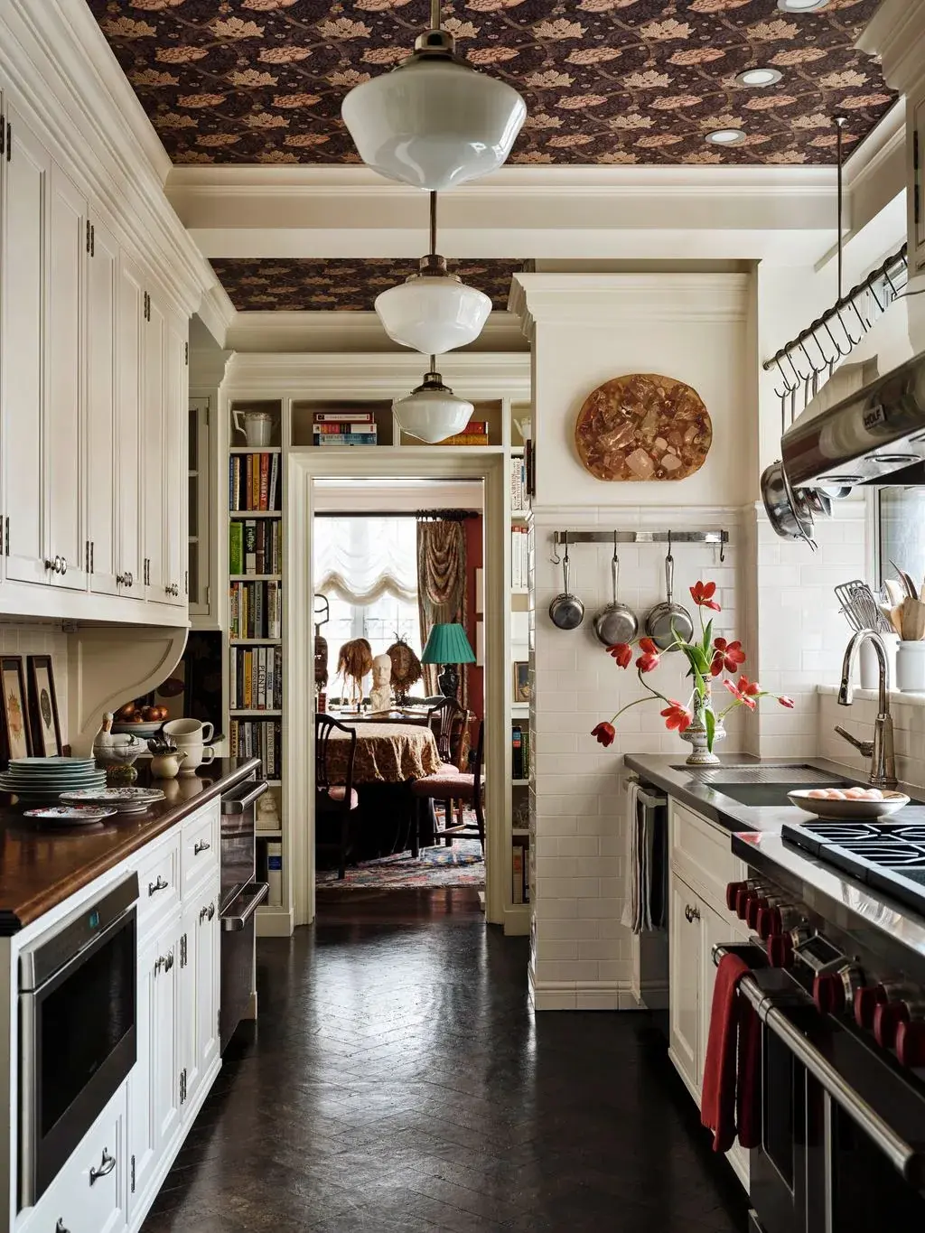 Galley kitchen with dark floral wallpaper on the ceiling and three milk glass pendants