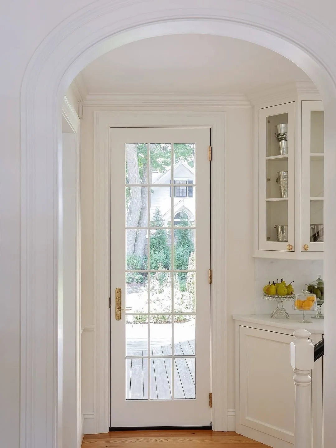 Shallow white arch over a glazed French door with brass hinges and handle