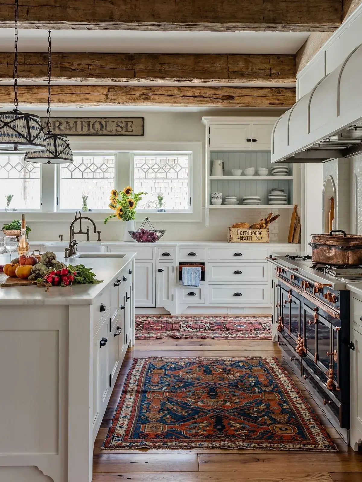 Wide pale reclaimed beams over a white farmhouse kitchen with Persian runners