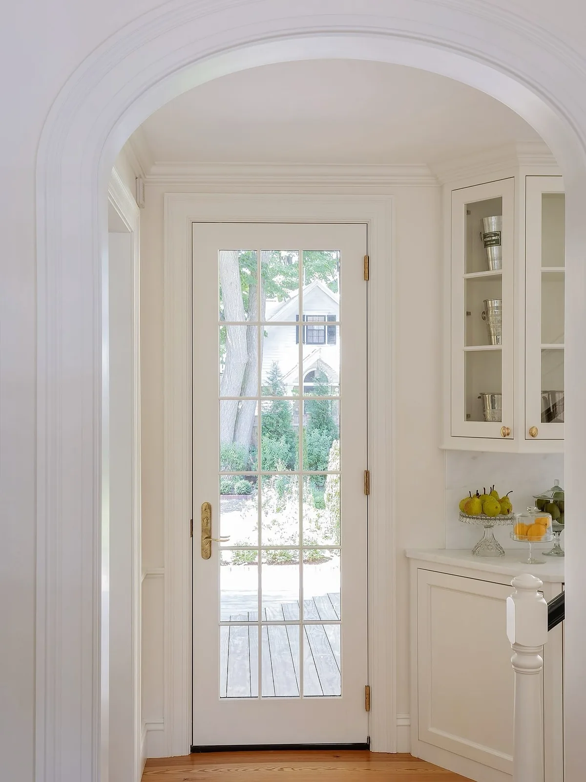 Glazed wall cabinet with brass knobs above a marble counter with green pears