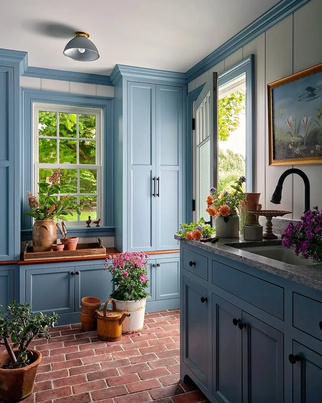Pale blue pantry kitchen with a brick floor, terracotta pots and a stone worktop