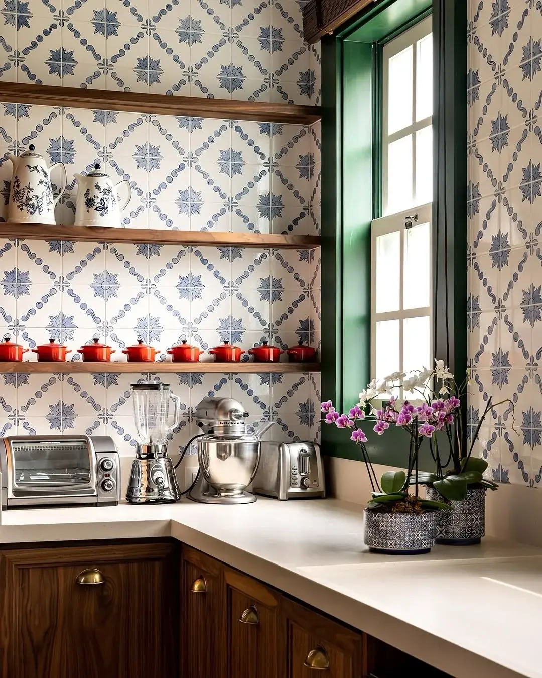 Timber kitchen with blue and white patterned tile, a green window frame and walnut shelves