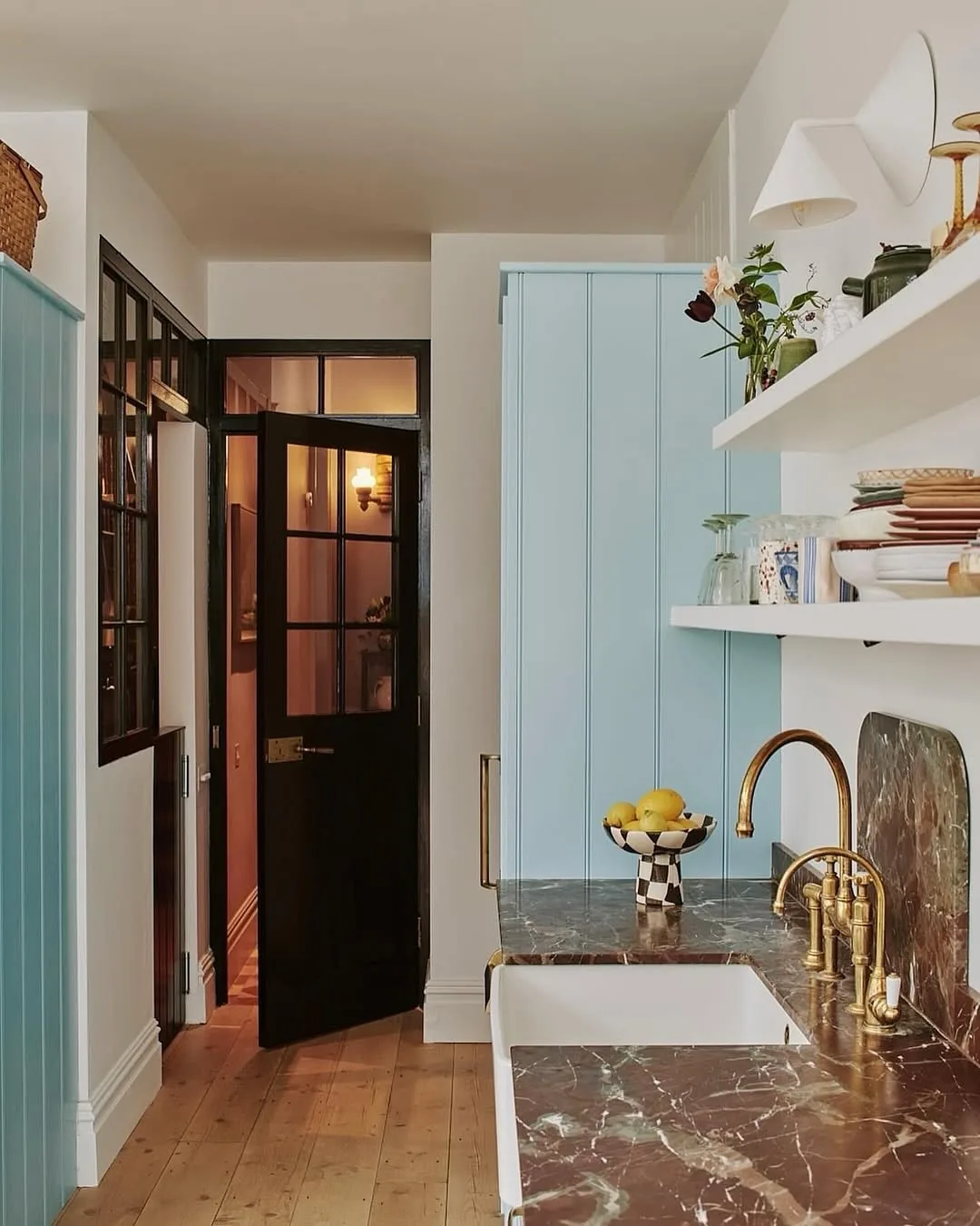 Narrow kitchen with a pale blue cupboard, burgundy marble worktop and brass taps