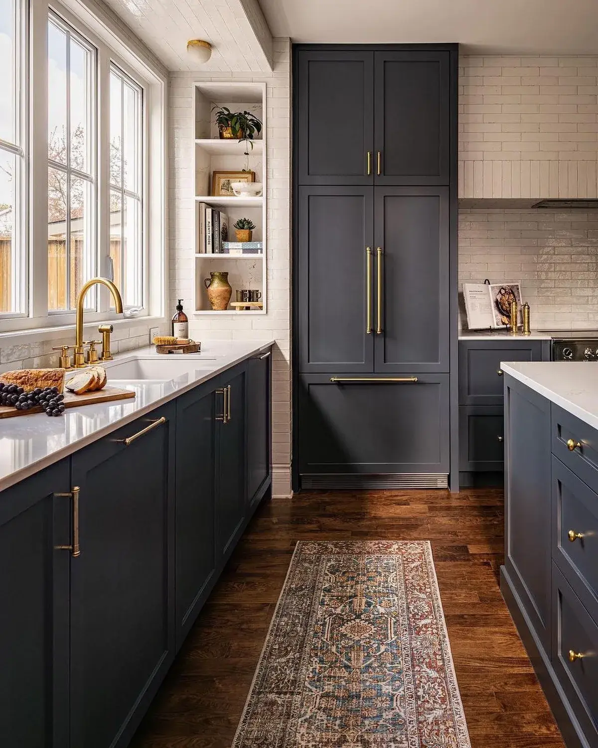 Deep navy galley kitchen with tall cabinets, brass pulls and a patterned runner