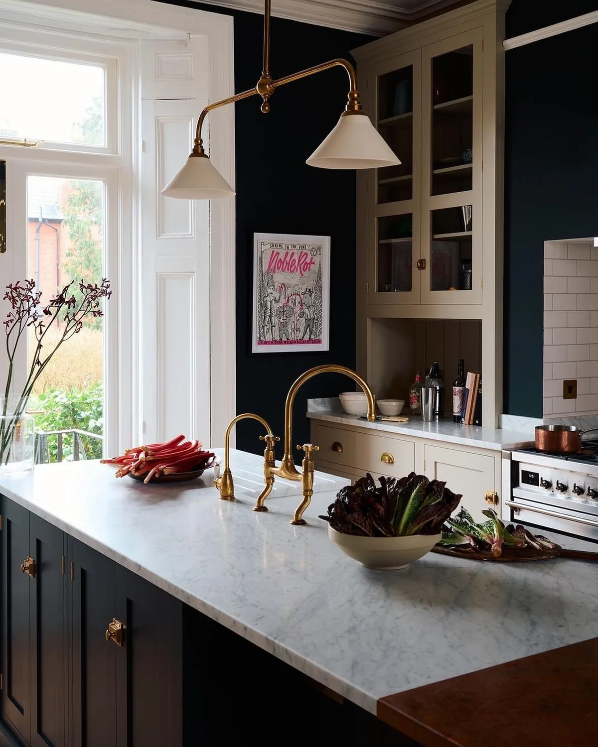 Dark panelled kitchen with a white marble island, brass taps and twin pendants