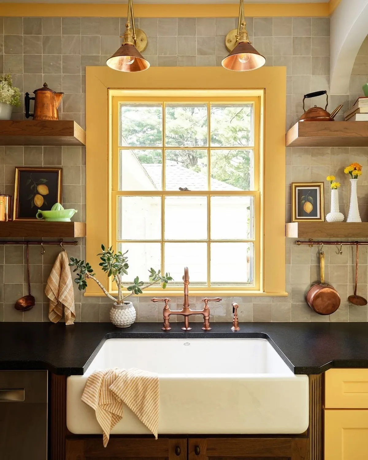 Mustard yellow window architrave over a Belfast sink with copper tap and open oak shelves