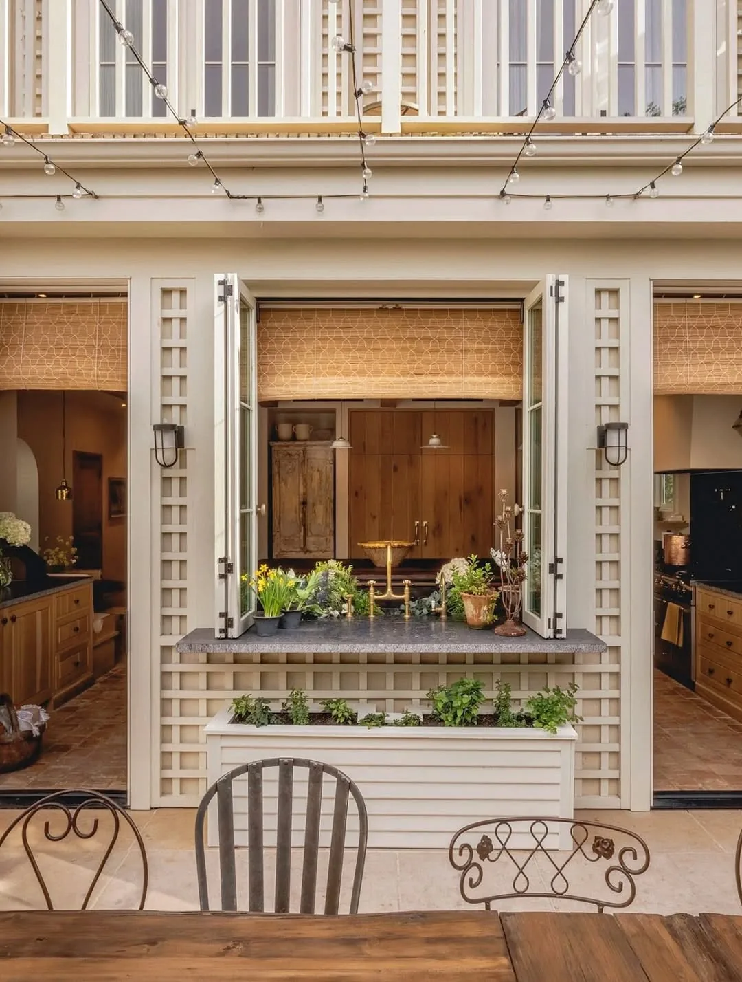 Open kitchen servery hatch with bamboo blind, stone sill counter and metal chairs outside