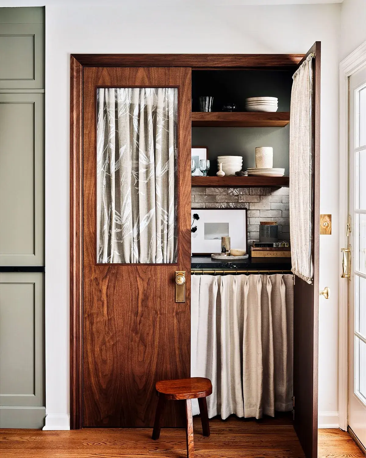 Walnut pantry doors with curtained glass and open shelves above curtained storage