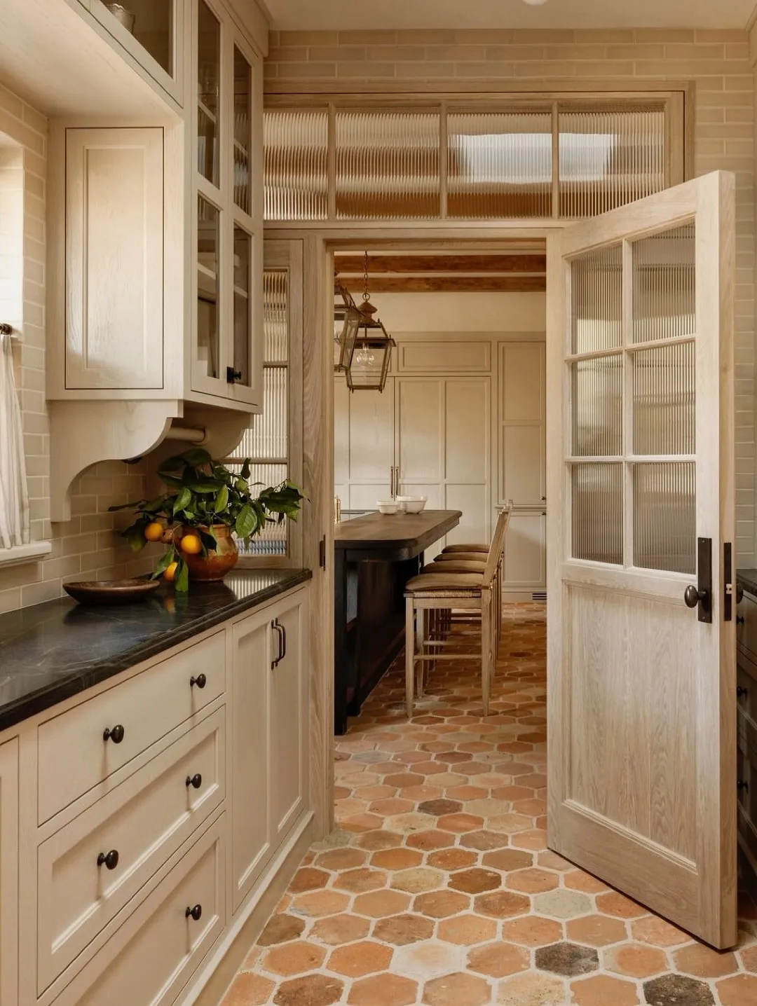 Cream pantry with reeded glass doors and terracotta hexagon floor opening to a dining area