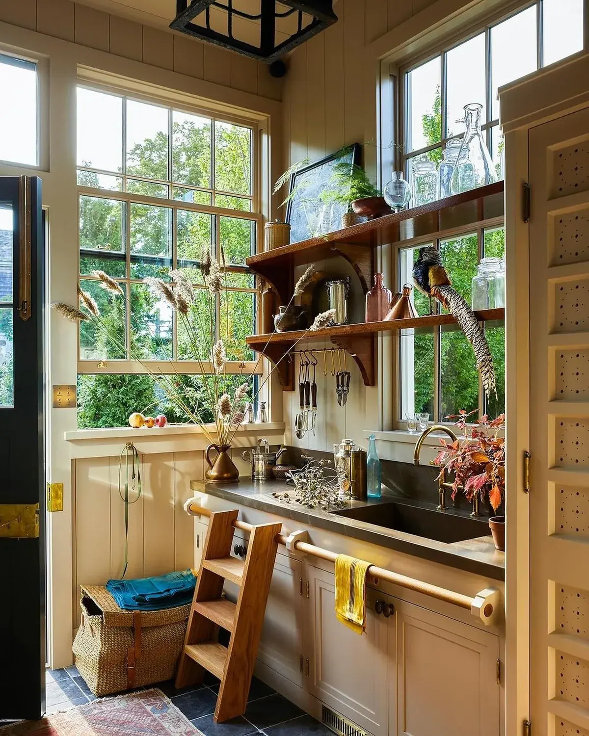 Timber scullery with dark sink, brass taps, open shelves and two windows
