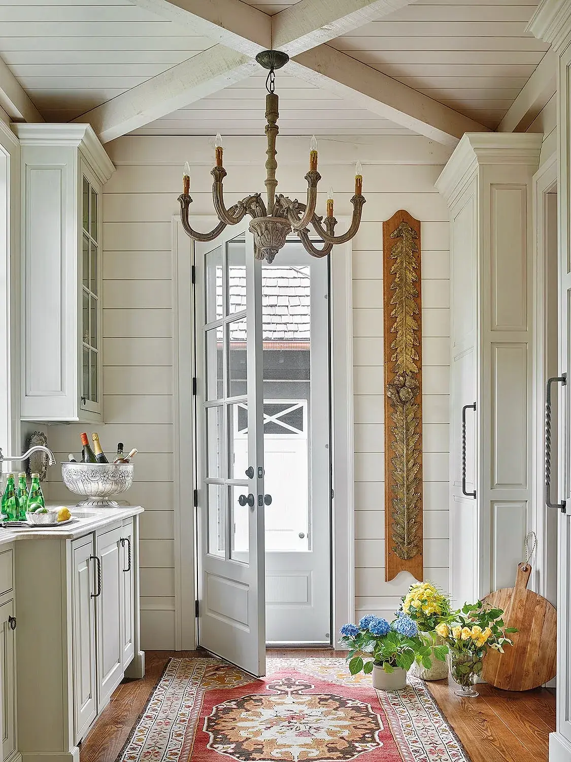 White shiplap pantry corridor with tall cupboards, French doors and a rug