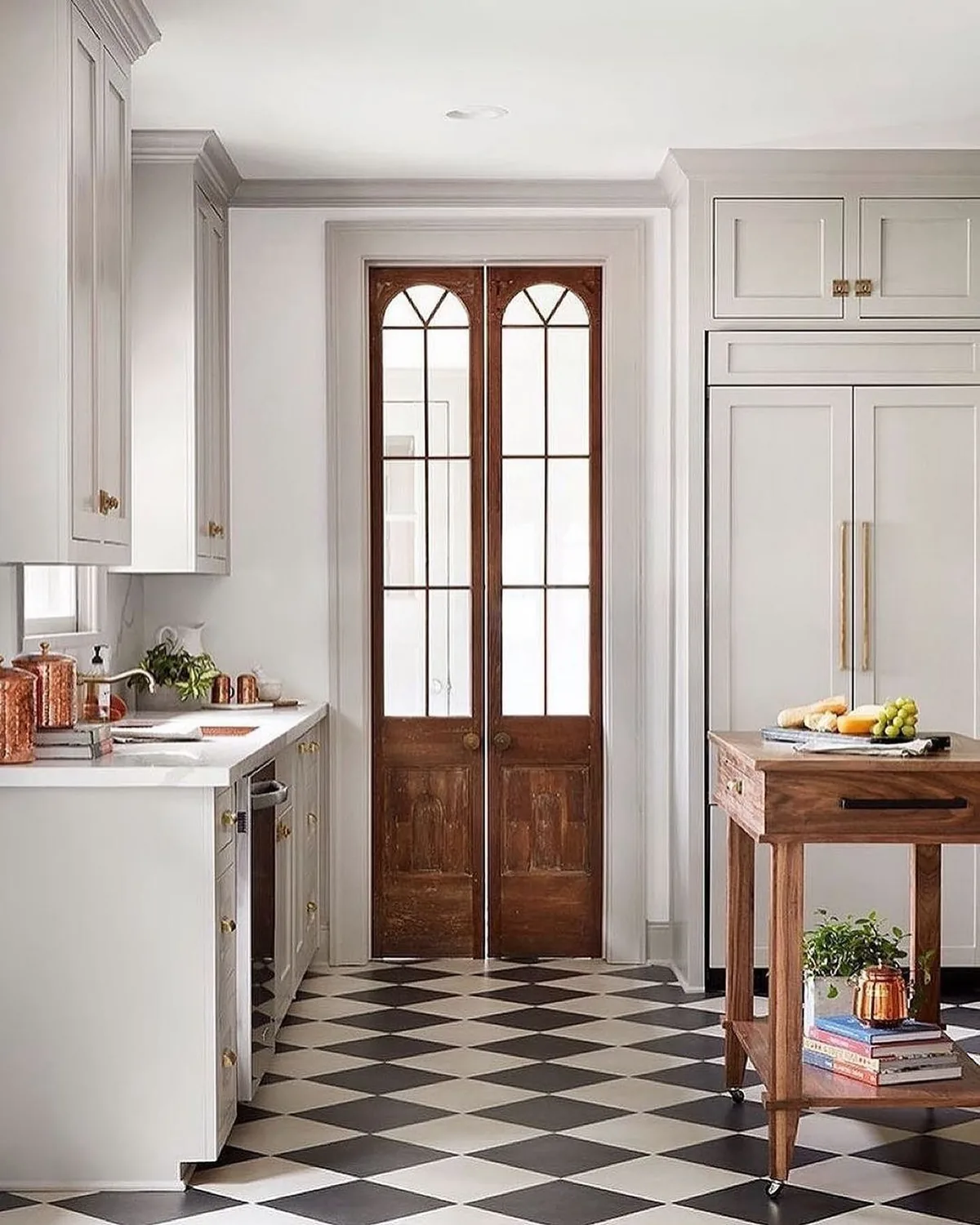 White kitchen with a black and white chequered floor and a timber island