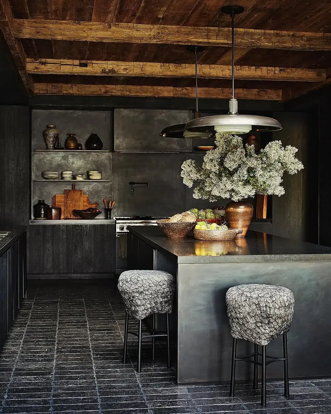 Dark kitchen with charcoal timber cabinets, a patinated metal island and a rough timber ceiling