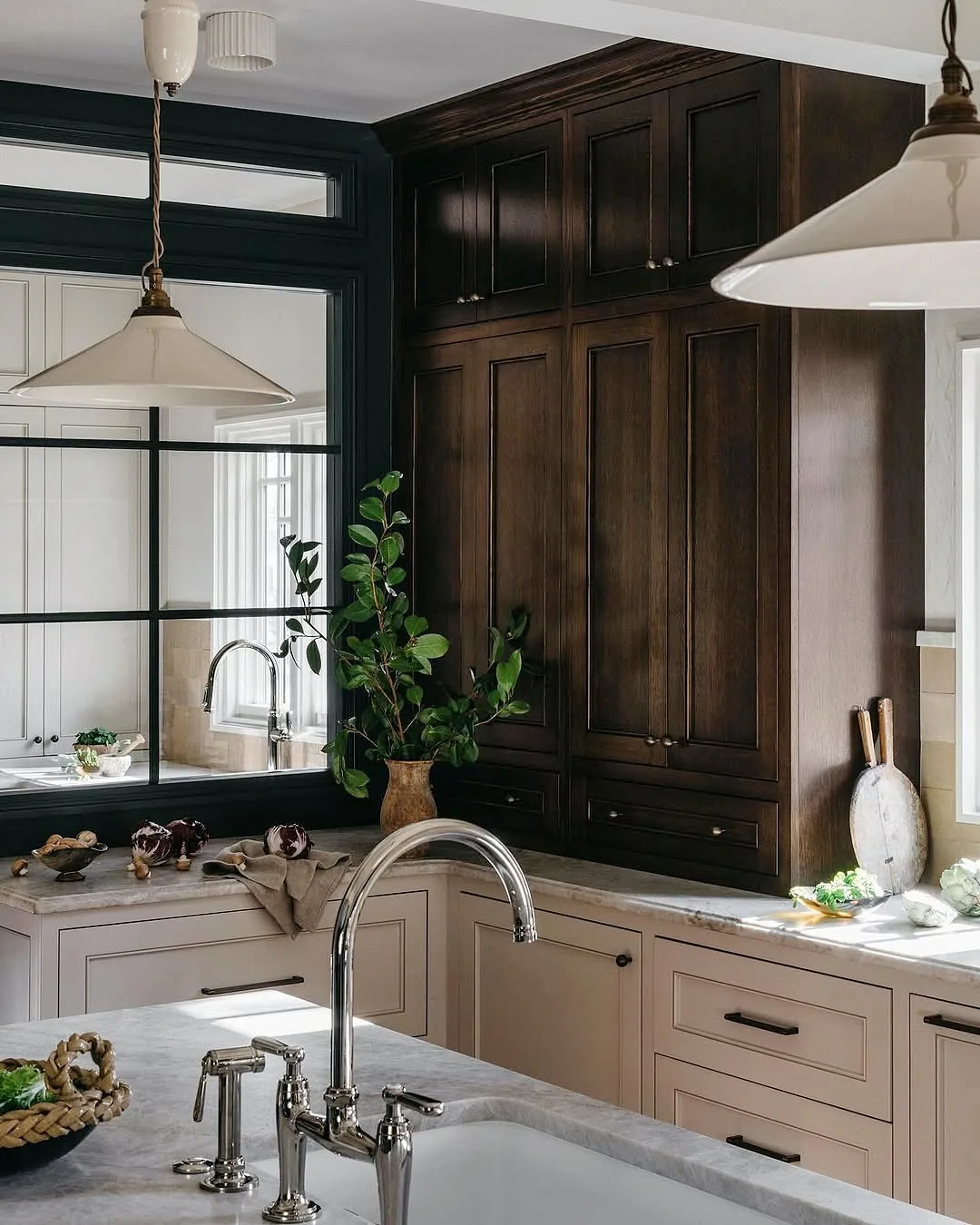 Cream kitchen with a tall dark timber larder and a black framed interior window