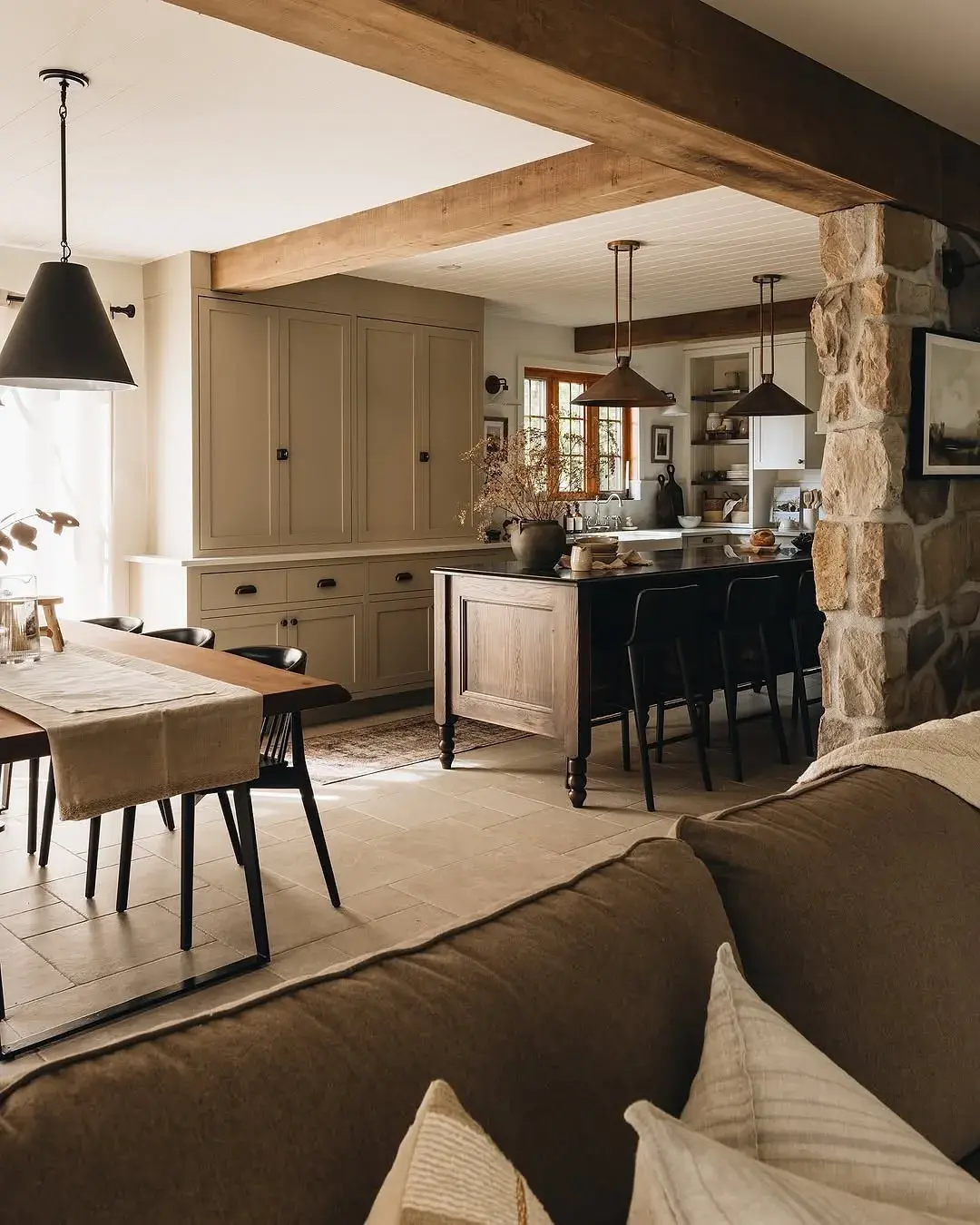 Open plan kitchen with stone pier, dark timber island and oak beams
