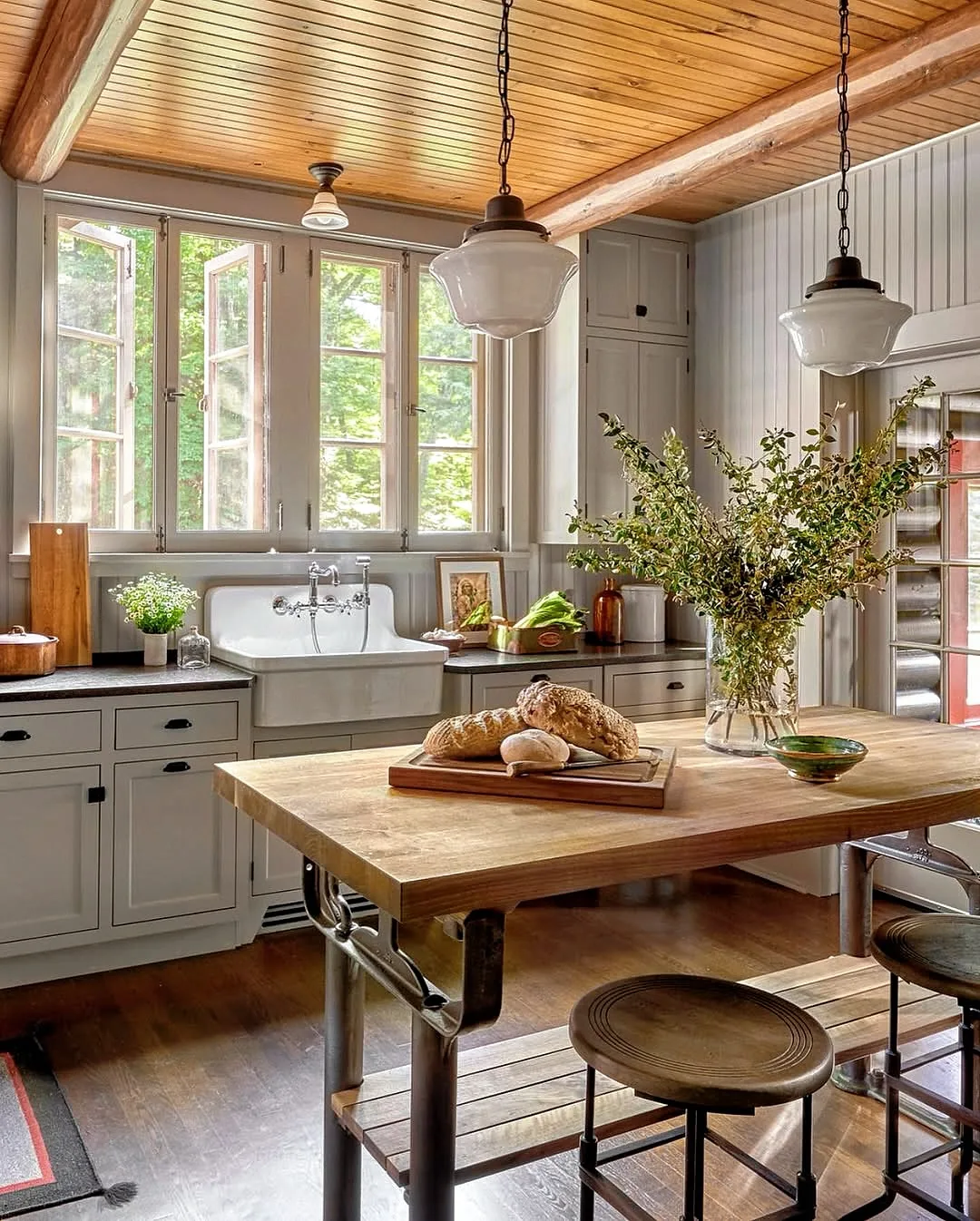 Pine island table on cast iron legs with bread, stools and a Belfast sink behind