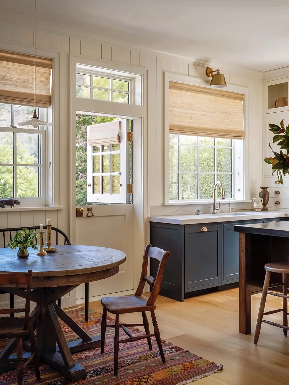 Cream kitchen with stable door, round timber table and dark blue island units