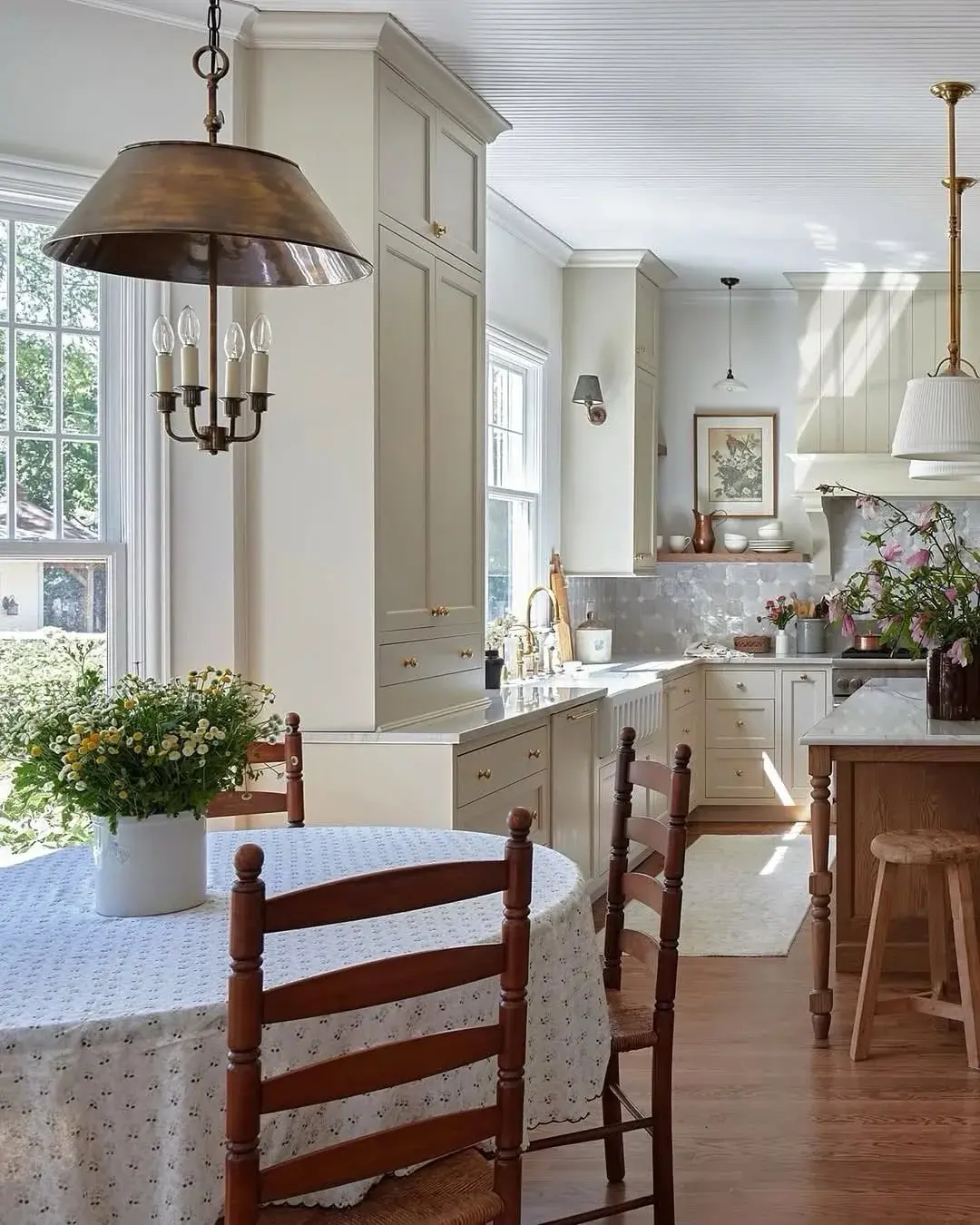 Bright bay with round cloth table, ladderback chairs and aged copper pendant