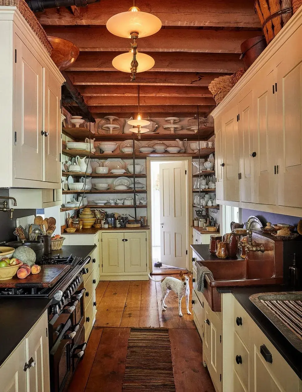 Beamed galley kitchen with a copper apron sink and cream cabinets