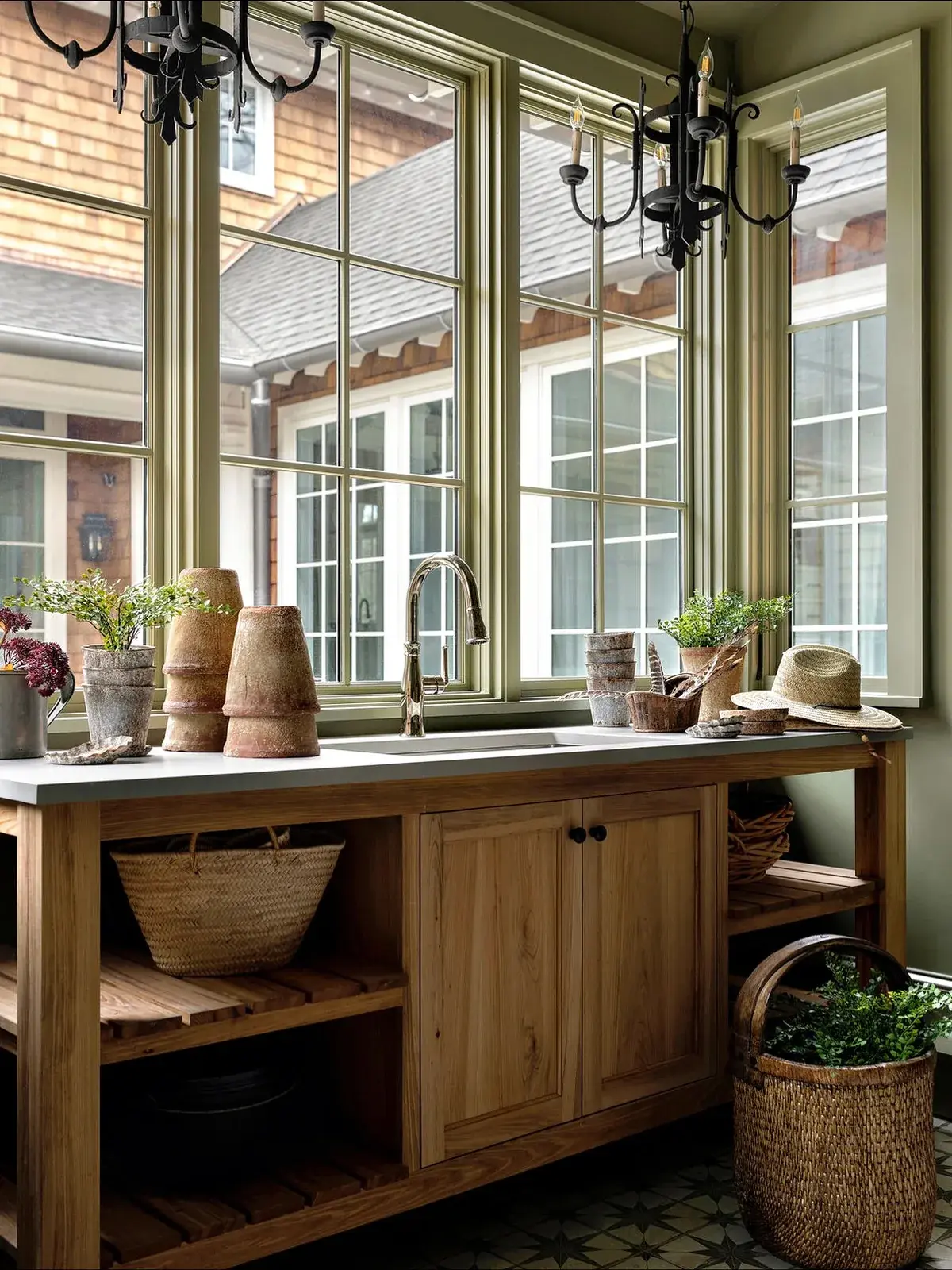 Freestanding oak potting bench with an inset sink under green framed windows
