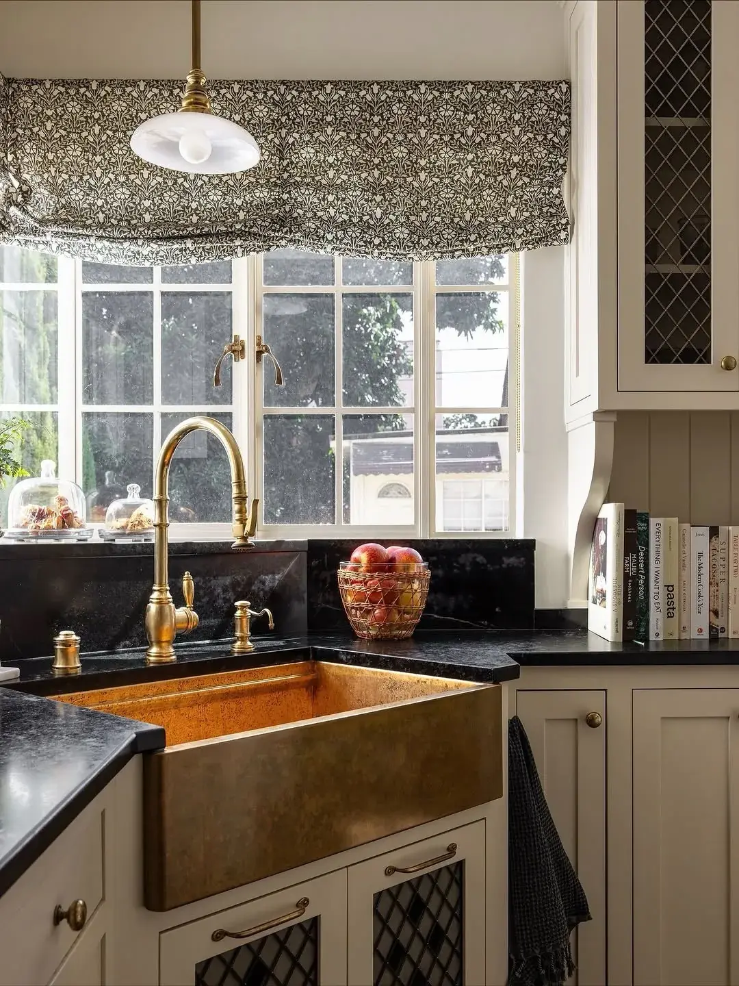Hammered brass apron sink with matching brass tap and black granite surround