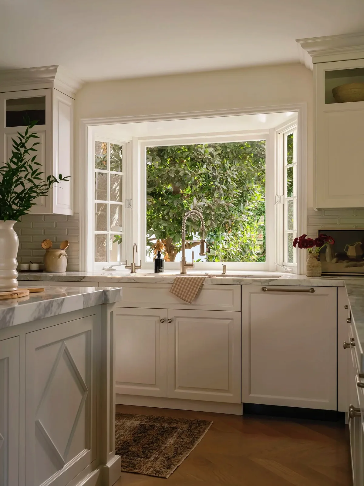 White shaker kitchen with bay window joinery, panelled island end and oak floor